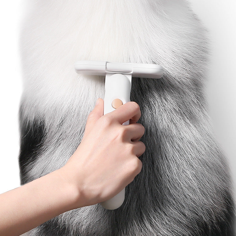 Person using a white grooming brush on a gray fur surface
