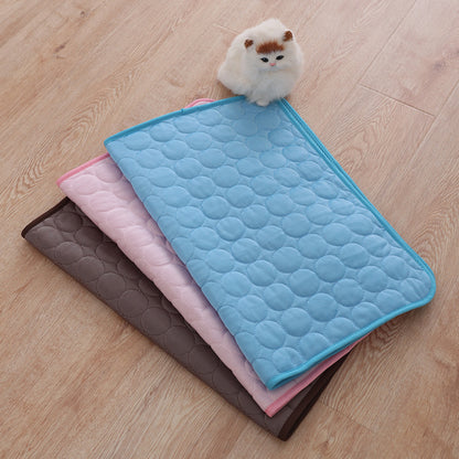 Three quilted mats in blue, pink, and brown on a wooden floor with a small plush toy.