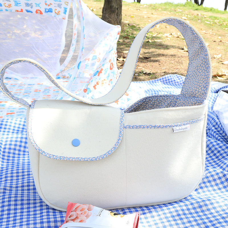 White handbag with blue accents on a checkered blanket outdoors