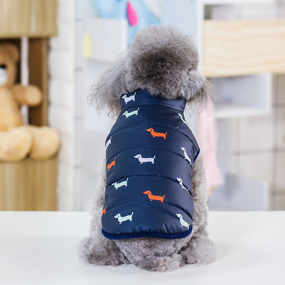 Small dog wearing a navy blue puffer vest with dog pattern indoors.