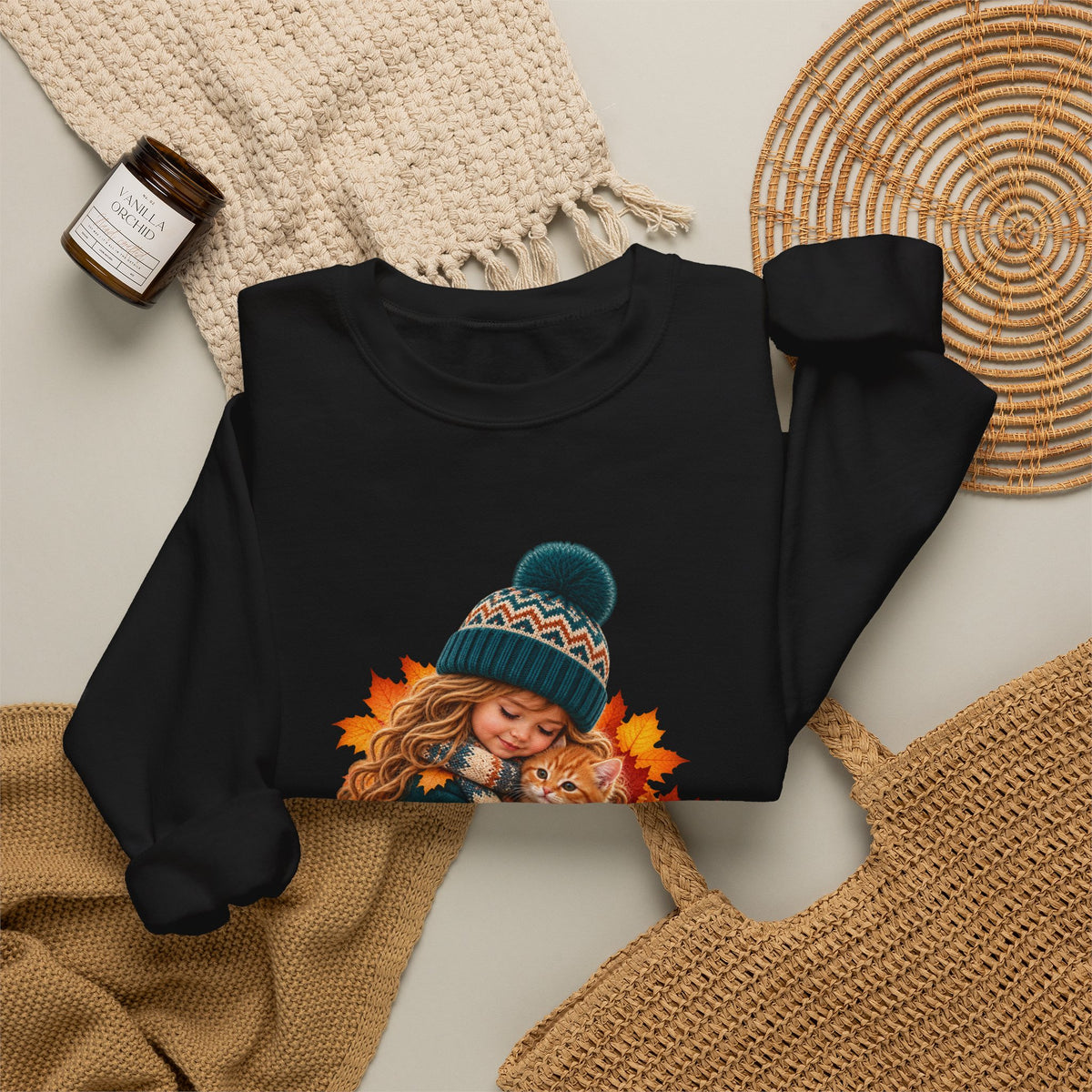 Folded black Golden Moments girl and kitten sweatshirt styled with neutral knit accessories
