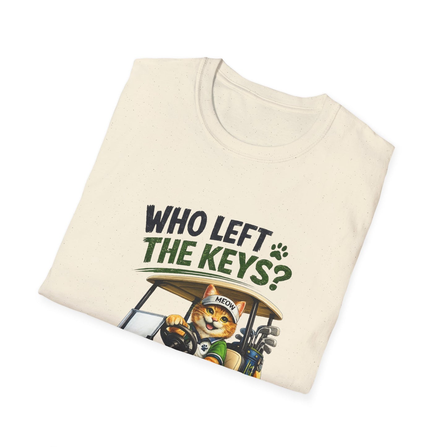 A folded cream-colored t-shirt with a graphic print of a cartoon cat driving a golf cart, with the text 'WHO LEFT THE KEYS?' in dark green and black lettering.