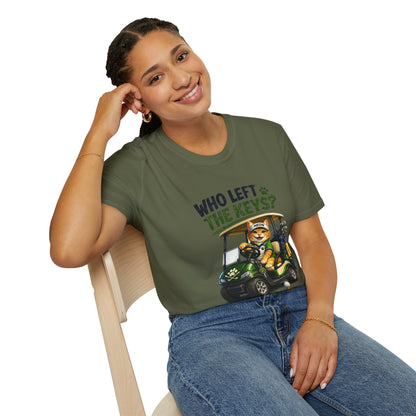 A woman wearing an olive green graphic t-shirt with a cartoon cat in a golf cart and the text 'WHO LEFT THE KEYS?' sitting on a light wood chair against a white background.