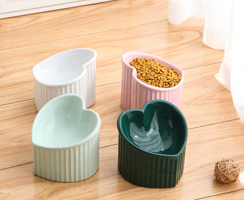 Heart-shaped ceramic bowls in various colors on a wooden floor.