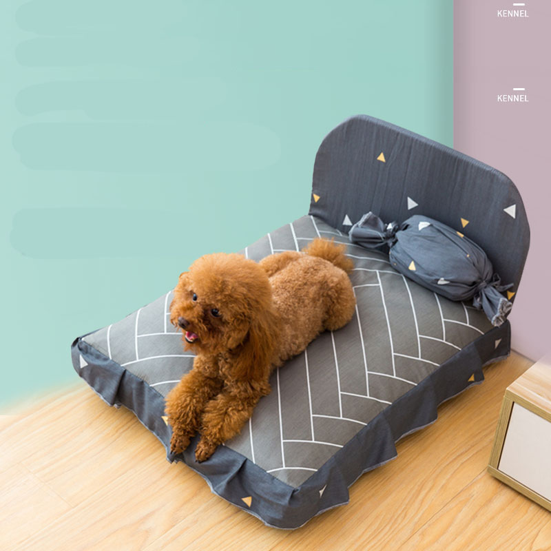 Dog lying on a gray pet bed with geometric patterns against a light blue wall.
