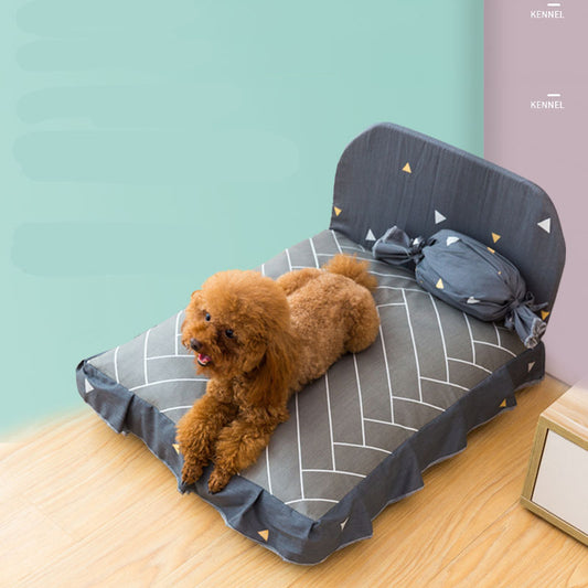 Dog lying on a gray pet bed with geometric patterns against a light blue wall.