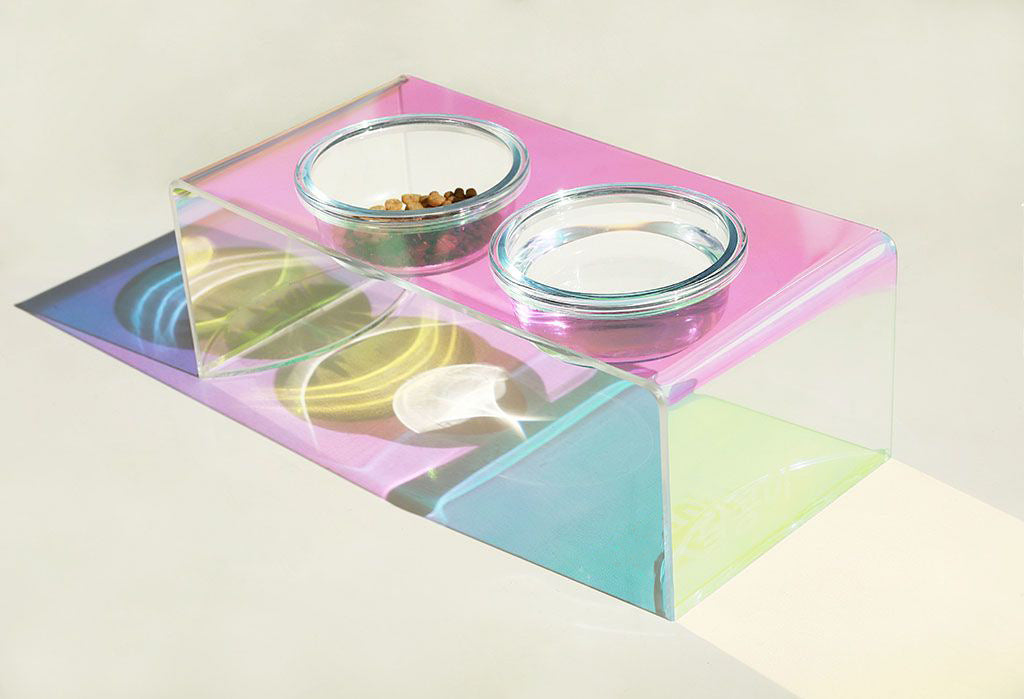 Iridescent pet food and water bowls on a pink tray with a light background
