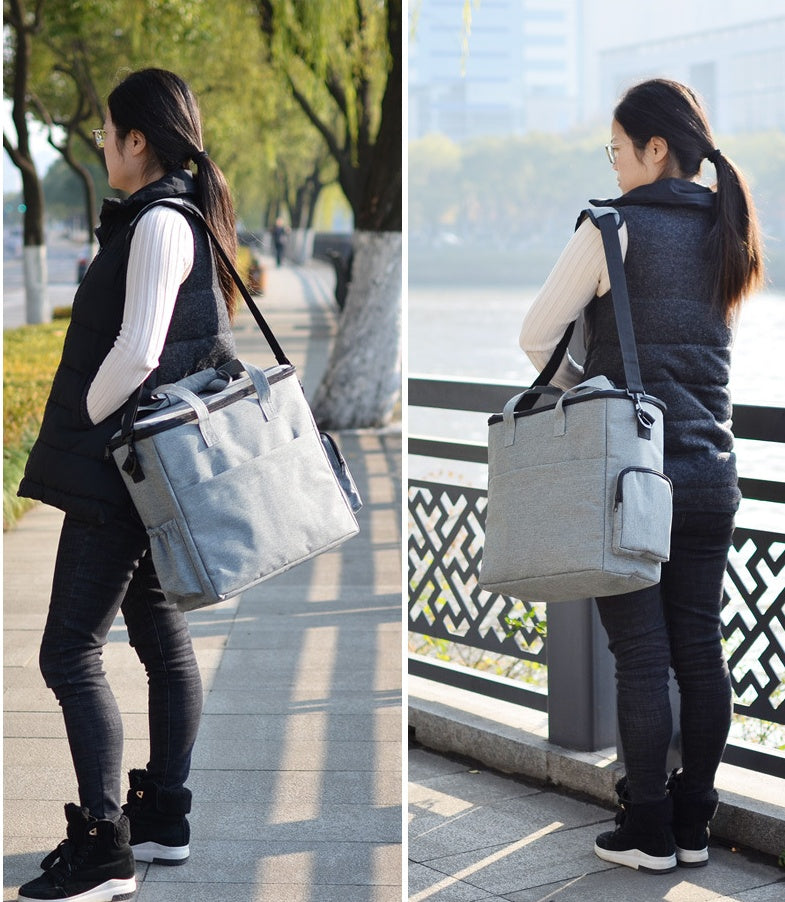 Woman carrying a gray insulated cooler bag outdoors.