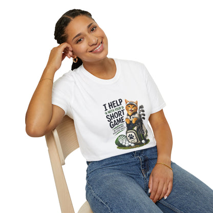 A white graphic T-shirt is displayed in a styled flat lay on a light beige surface. The shirt features a cartoon cat wearing a baseball cap and holding golf clubs, with the text 'I HELP WITH YOUR SHORT GAME BY STEALING GOLF BALLS.