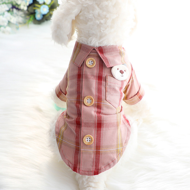 Pet wearing a pink plaid dress with buttons on a white background