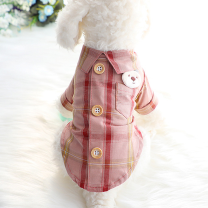 Pet wearing a pink plaid dress with buttons on a white background