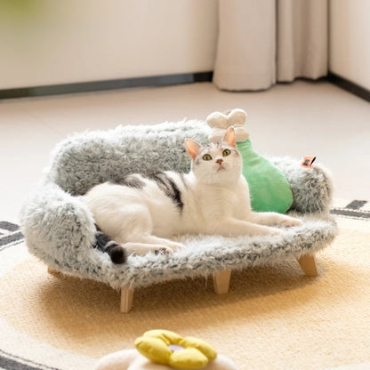 Cat lying on a small, fluffy pet bed with a plush toy in a cozy room.
