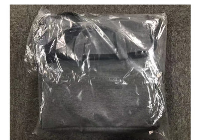Black backpack wrapped in clear plastic on a textured surface