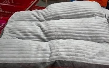Folded white textured blanket on a surface with a blurred background
