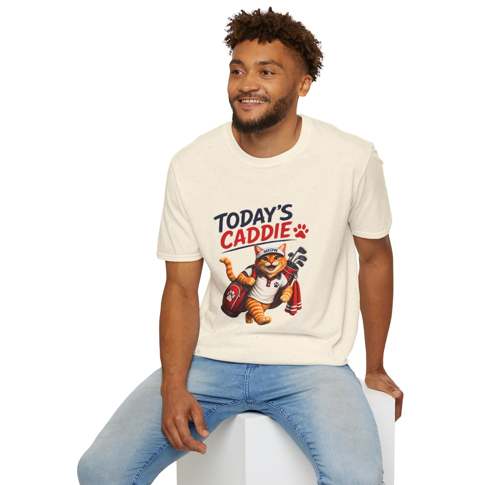 An natural short-sleeve crewneck t-shirt featuring a cartoon graphic of an orange tabby cat wearing a cap and holding golf clubs, with the text 'TODAY'S CADDIE' 