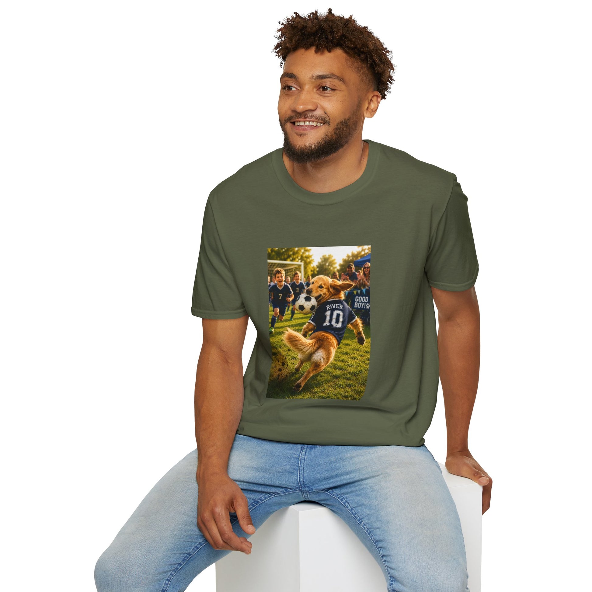 A man wearing an olive green t-shirt with a custom graphic print of a dog playing soccer, seated on a white block against a white background.