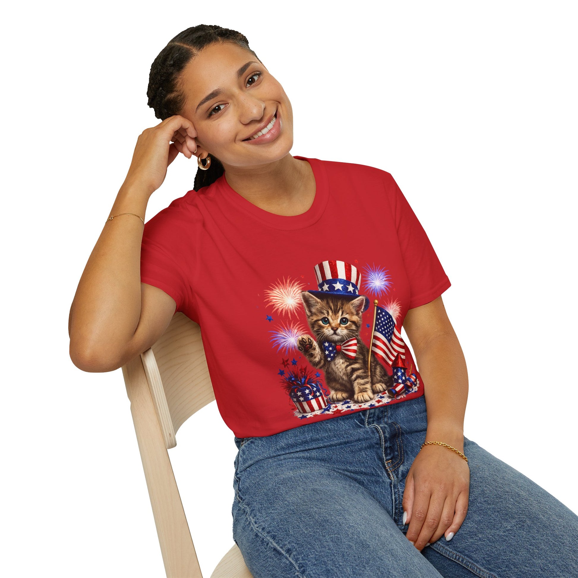 Person wearing a red t-shirt with a cat graphic holding an American flag and fireworks.