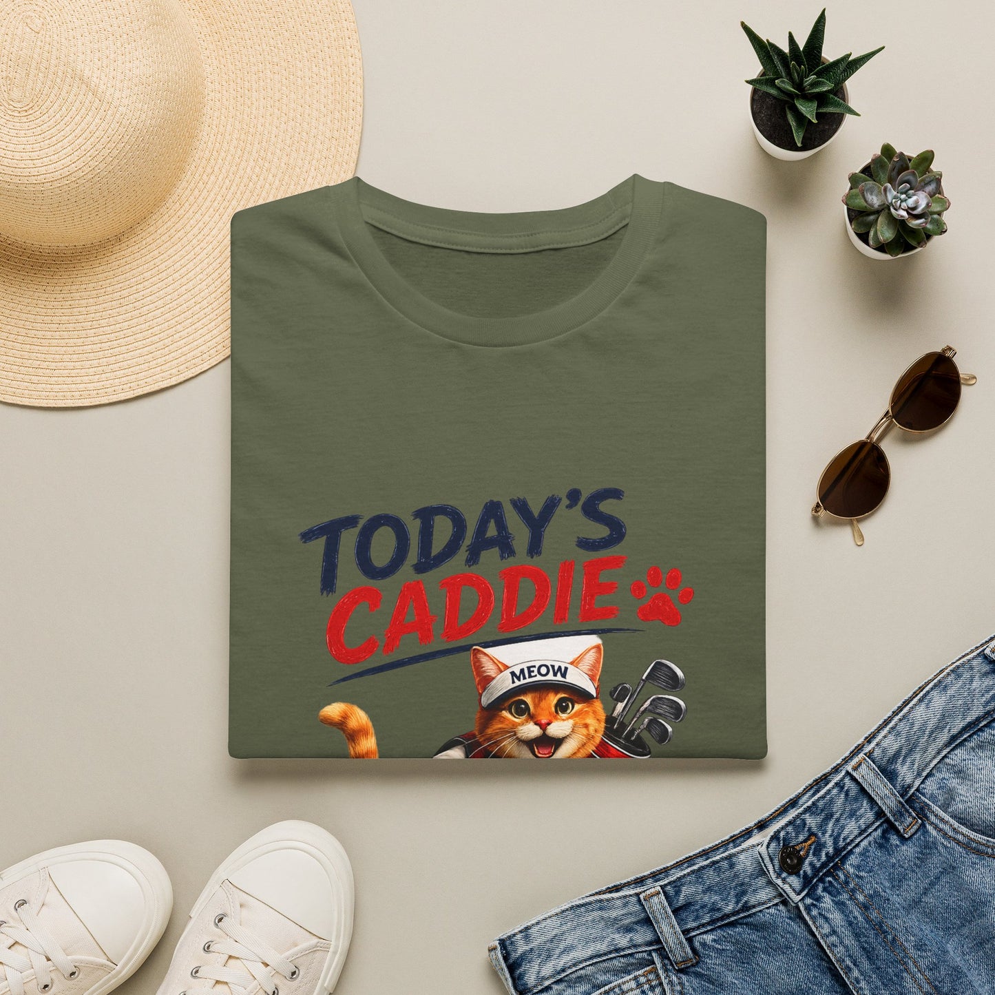 An olive green short-sleeve crewneck t-shirt featuring a cartoon graphic of an orange tabby cat wearing a cap and holding golf clubs, with the text 'TODAY'S CADDIE' 