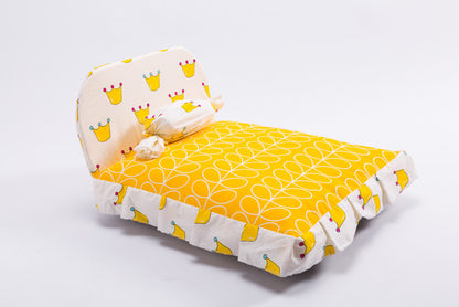 Yellow baby crib bumper with crown pattern on a white background