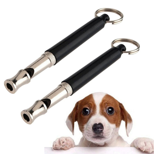 Two black dog whistles with silver accents on a white background, with a puppy peeking from below.