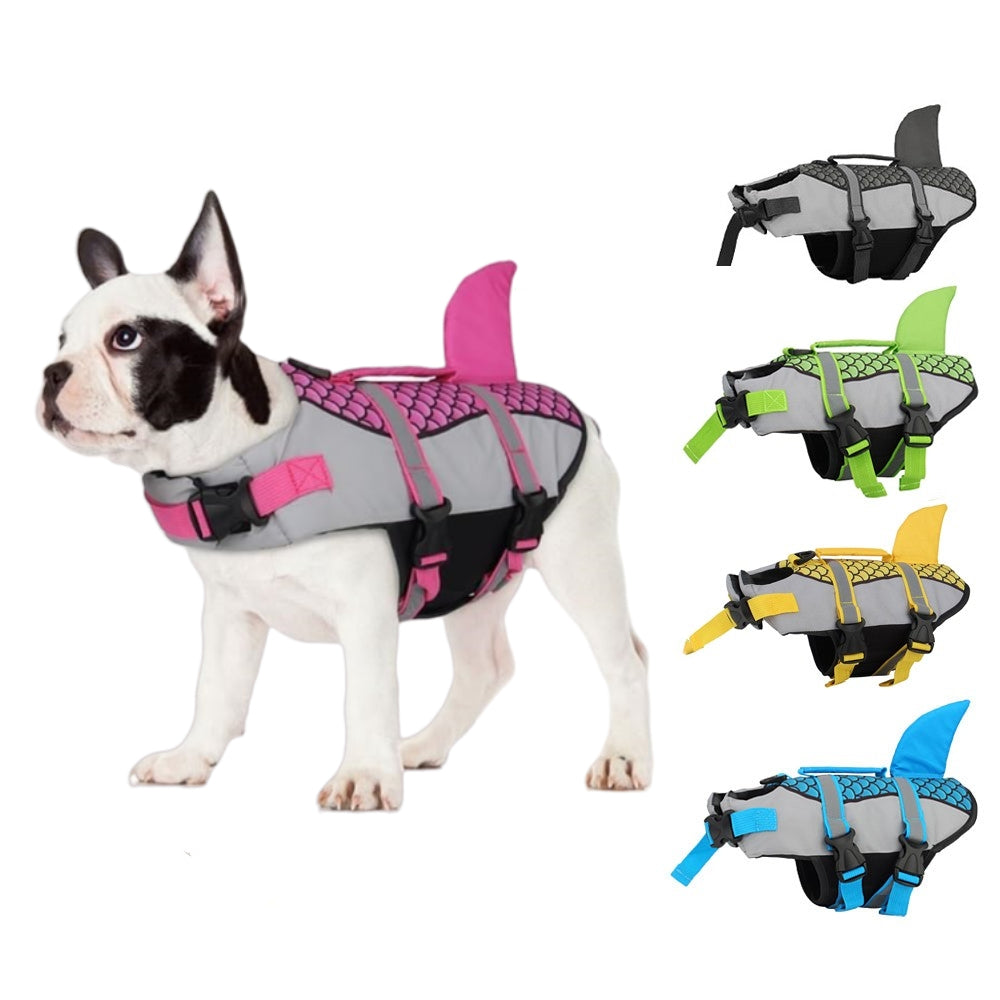 Dog wearing a gray and pink life jacket with shark fin design, surrounded by other colorful life jackets on a white background.
