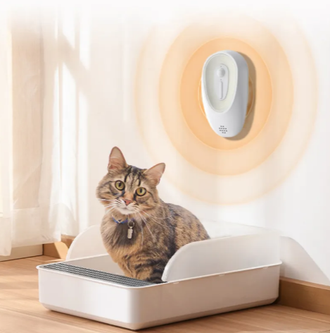 Cat sitting on a litter box with a wall-mounted device in the background