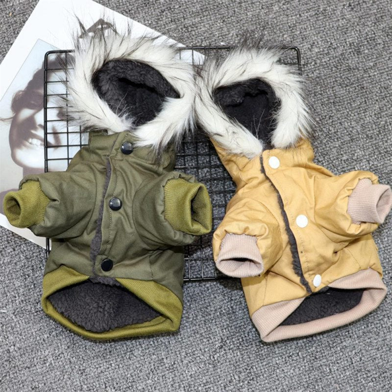 Two small dog coats, one green and one yellow, with fur-lined hoods on a textured surface.