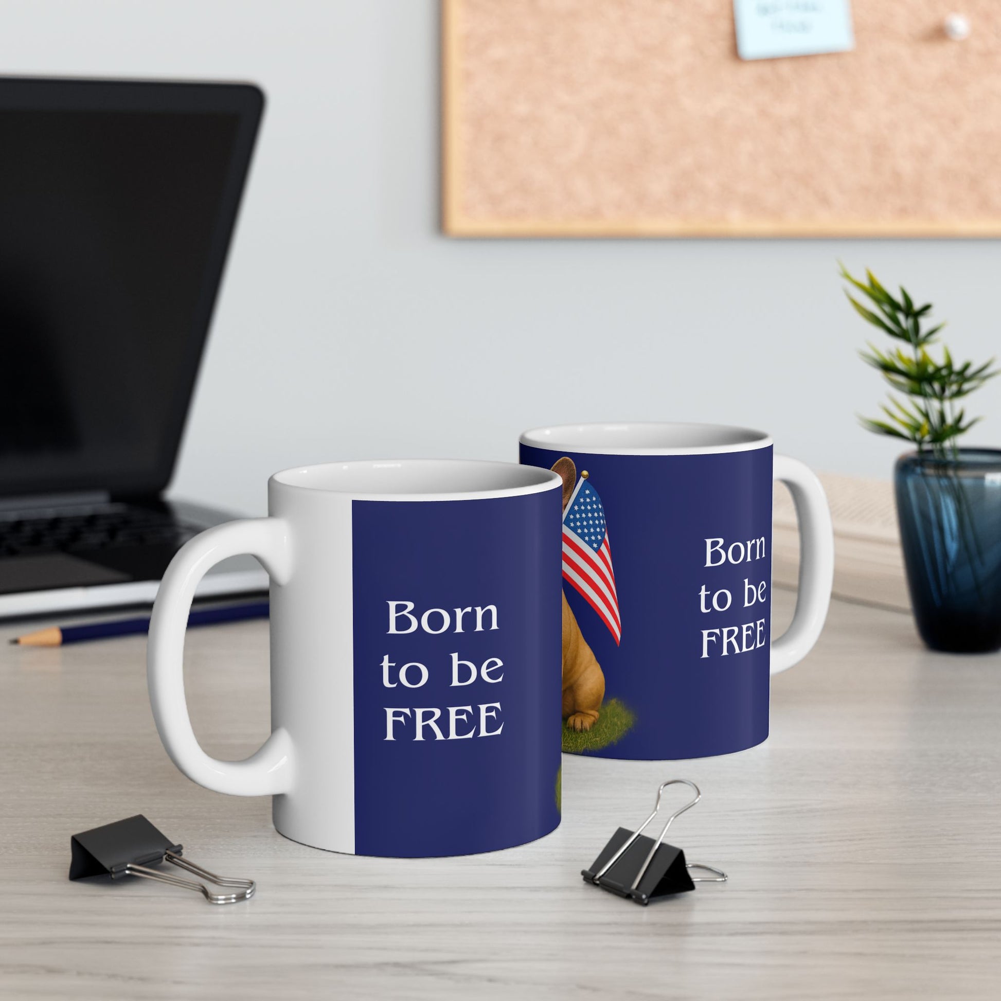 Two mugs with 'Born to be FREE' text on a desk with office items.