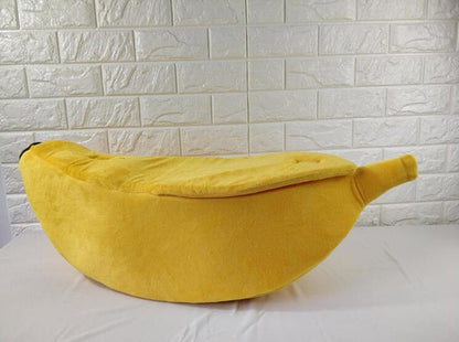 Yellow bean bag shaped like a banana against a white brick wall.