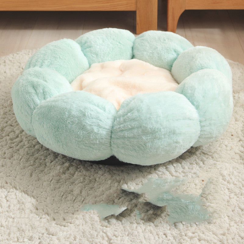 Round, plush pet bed in light blue color on a carpeted floor.