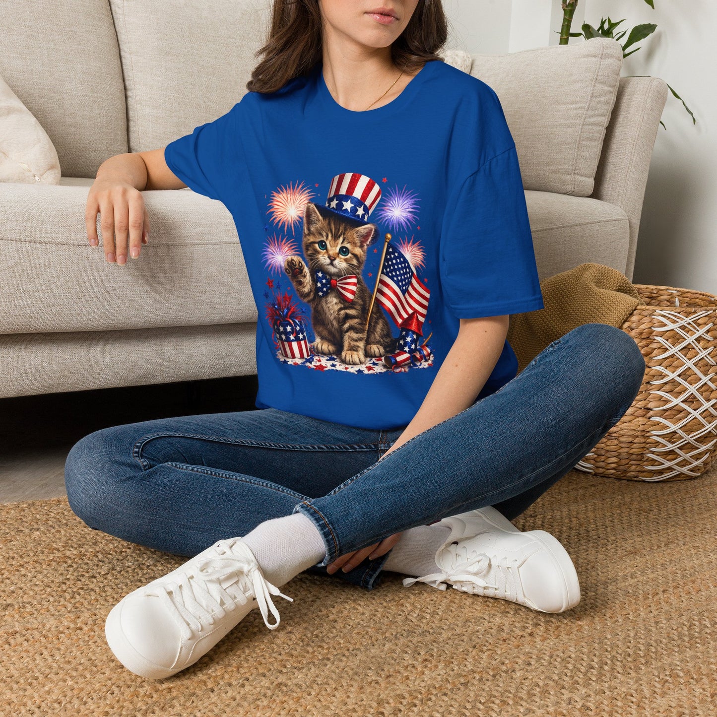 Person wearing a blue t-shirt with a graphic design sitting on a carpeted floor.