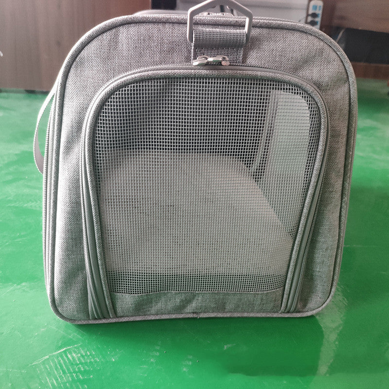 Gray pet carrier with mesh front on a green surface
