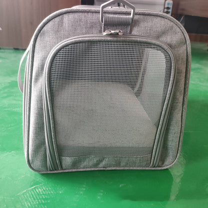 Gray pet carrier with mesh front on a green surface