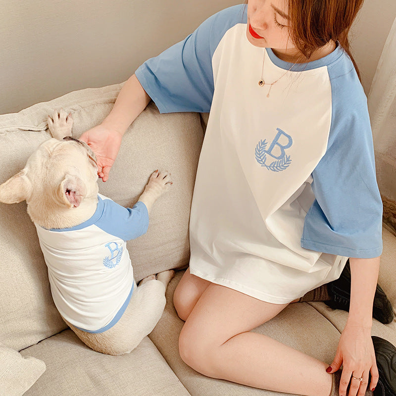 Person and dog wearing matching blue and white outfits with a logo on a couch.