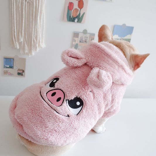 Dog wearing a pink pig-themed hoodie in a room with decor