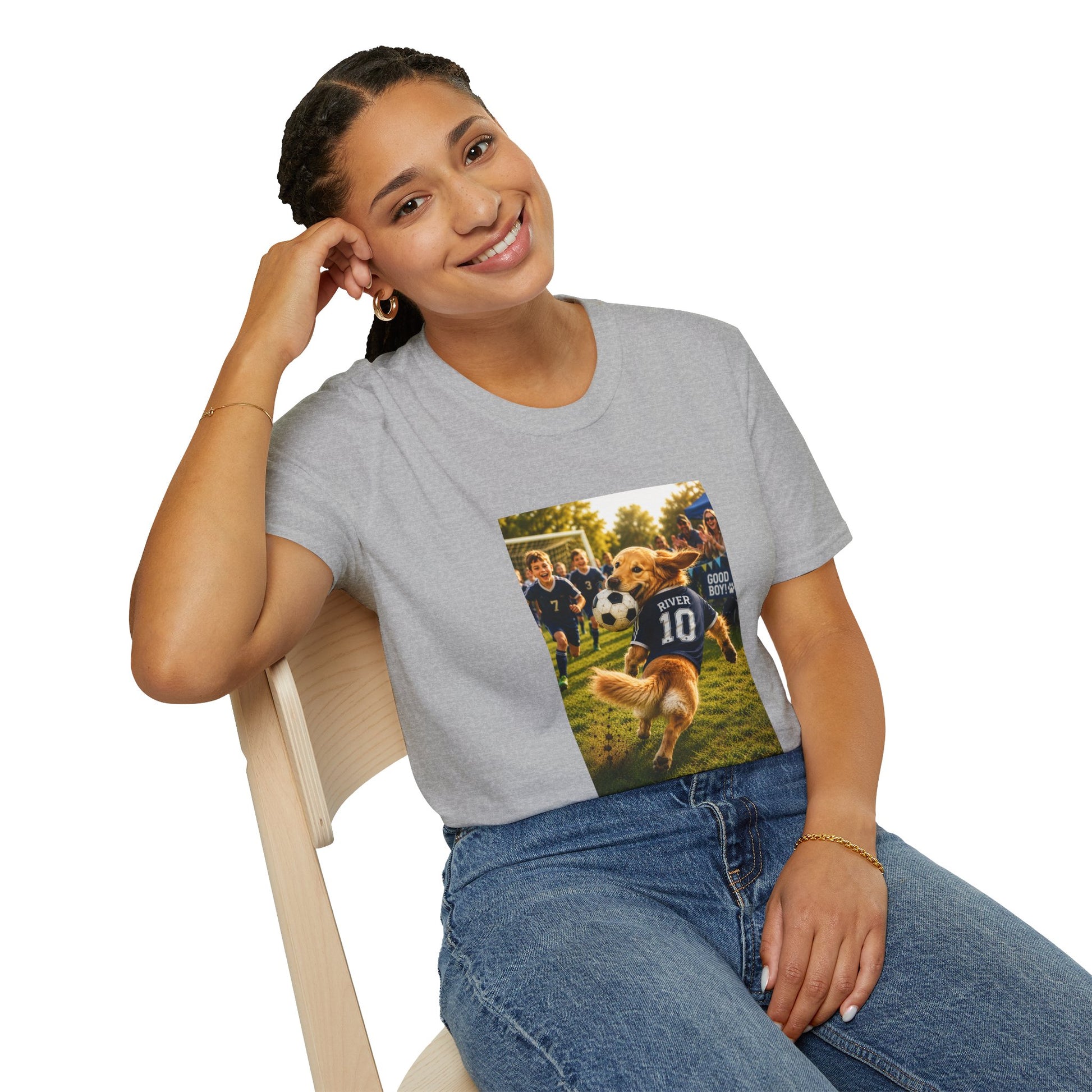 A woman sitting on a wooden chair wearing a heather gray t-shirt with a custom graphic print of a dog soccer game, paired with blue jeans against a white background.