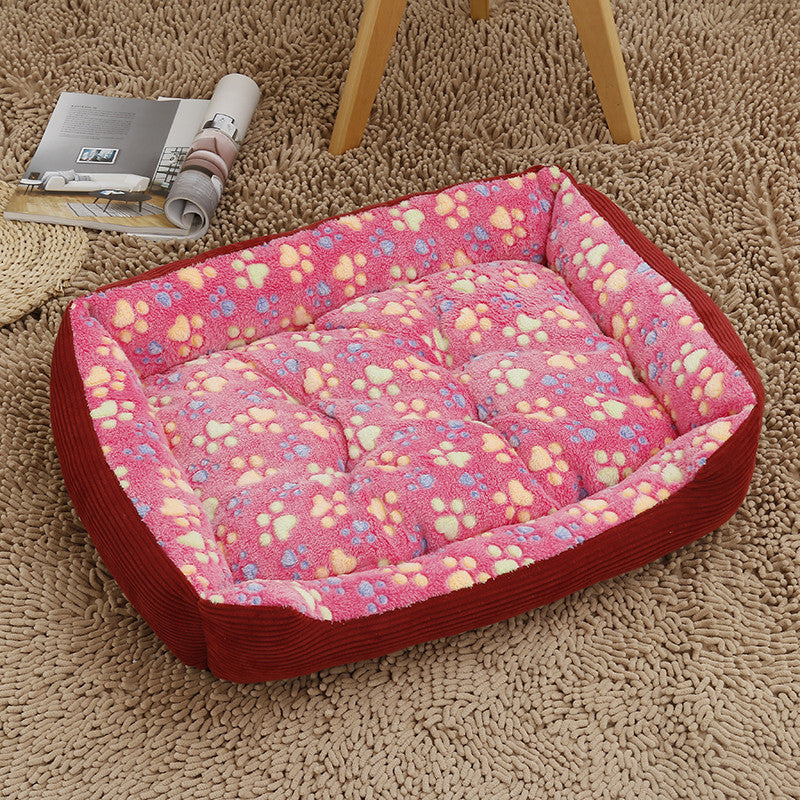Pink pet bed with paw print pattern on a beige carpet