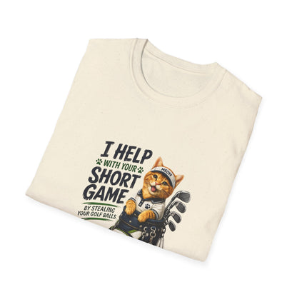 A natural color graphic T-shirt is displayed in a styled flat lay on a light beige surface. The shirt features a cartoon cat wearing a baseball cap and holding golf clubs, with the text 'I HELP WITH YOUR SHORT GAME BY STEALING GOLF BALLS.