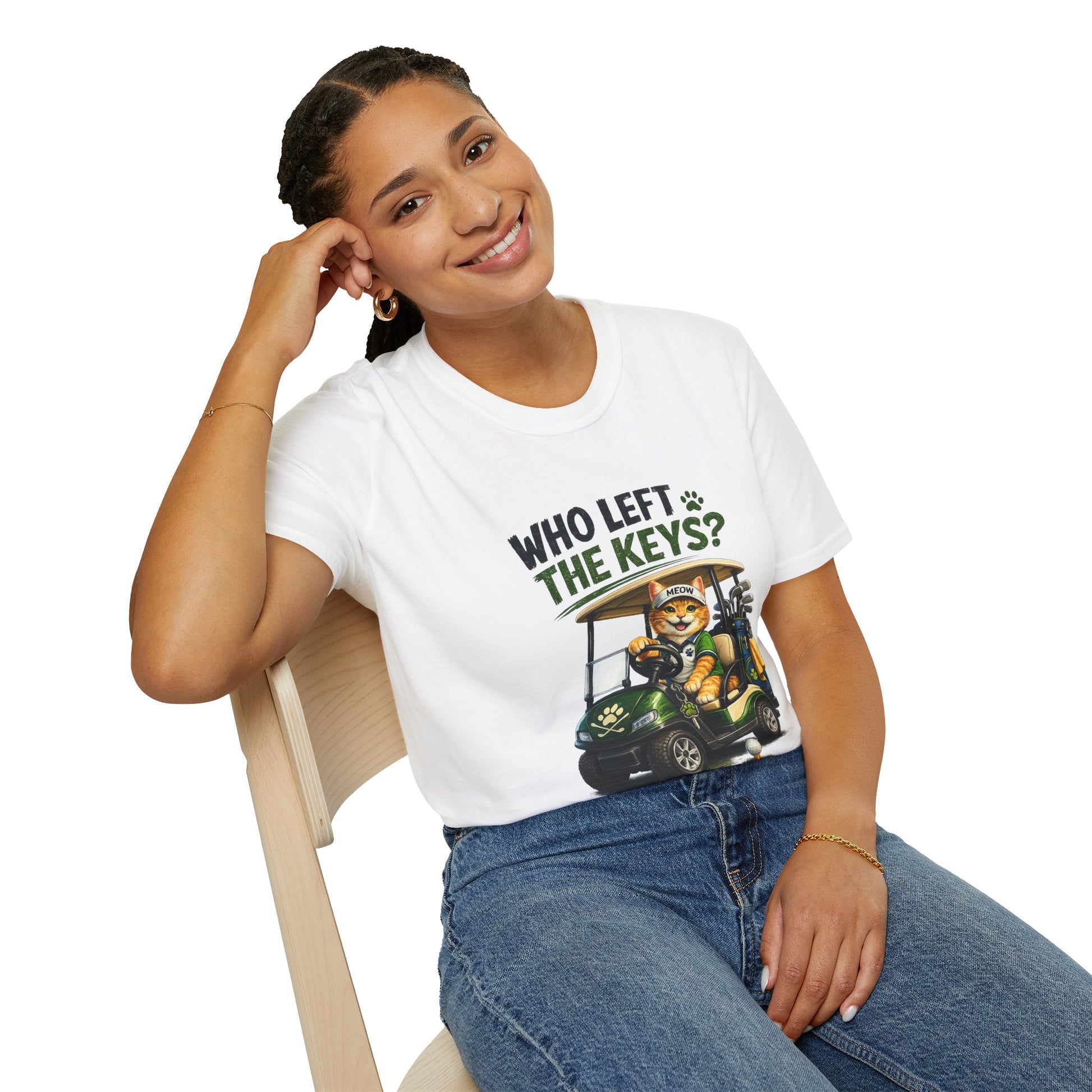 A woman wearing a white graphic t-shirt with the text 'WHO LEFT THE KEYS?' and a cartoon cat in a golf cart, sitting on a wooden chair against a white background.