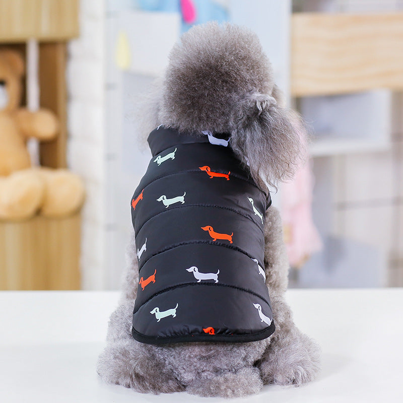 Dog wearing a black puffer vest with colorful dog patterns on a white surface.