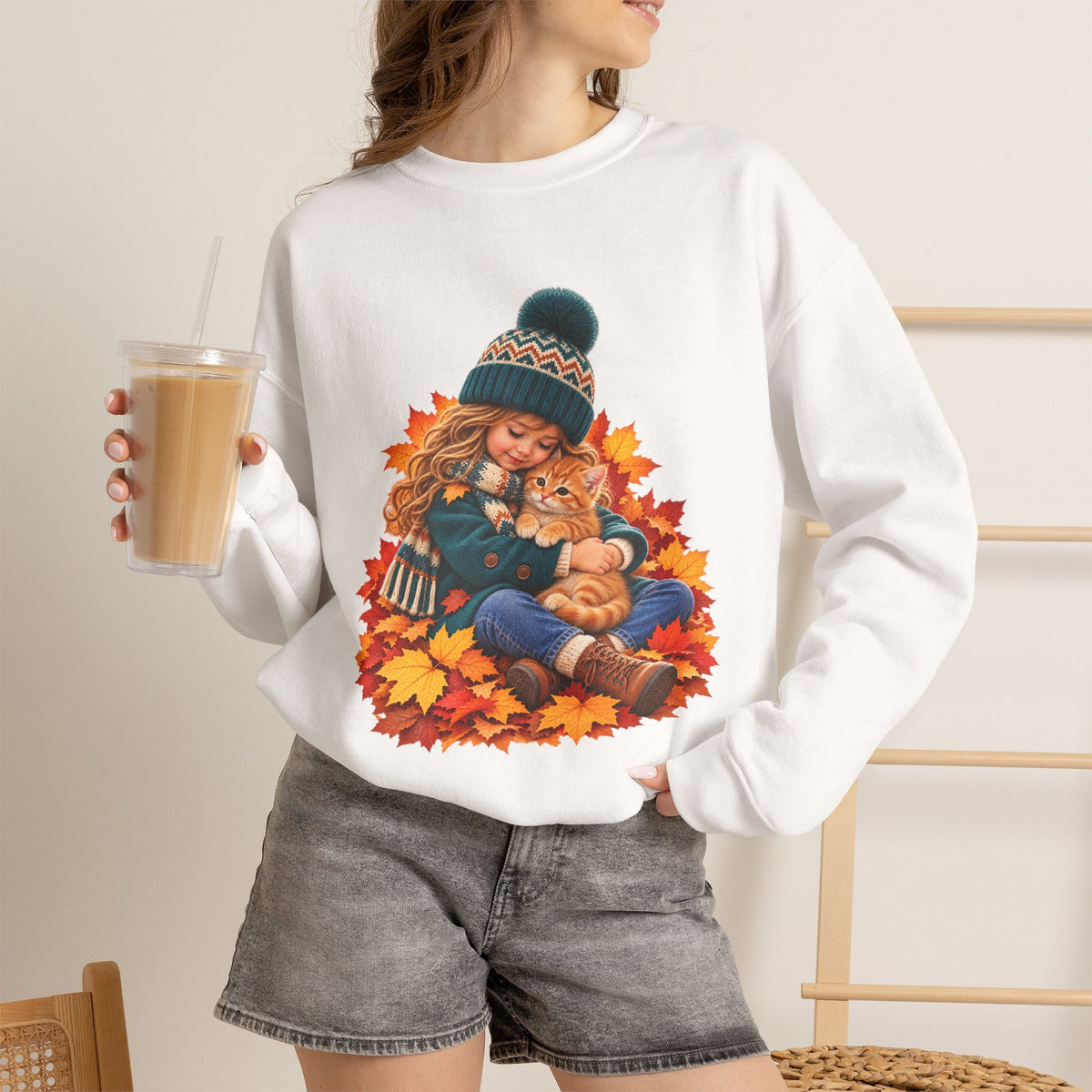 Woman holding a drink while wearing the White Golden Moments girl and kitten fall sweatshirt