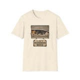 An off-white short-sleeve crewneck t-shirt featuring a graphic print of three cats sleeping in a window with a hanging sign that reads 'The Neighborhood Watch'.