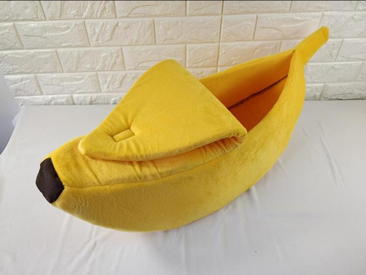 Yellow banana-shaped pet bed on a white surface with a light-colored wall background