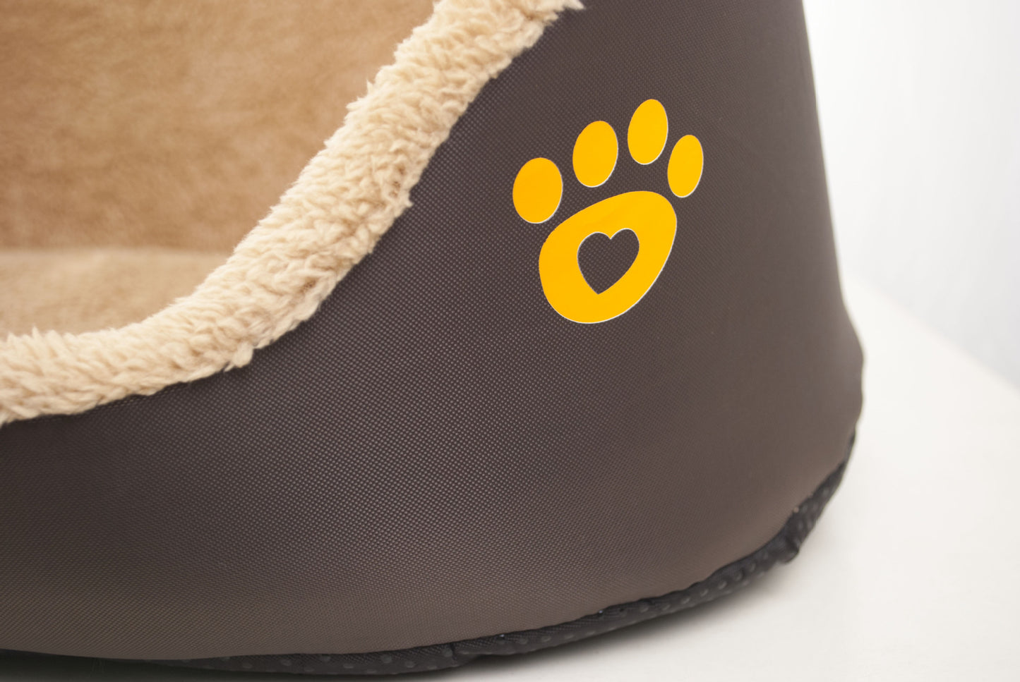 Brown pet bed with a yellow paw print logo on a white background