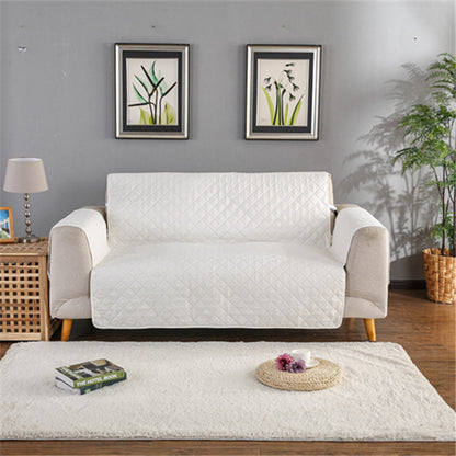 White sofa with a quilted cover in a living room setting with decor elements.