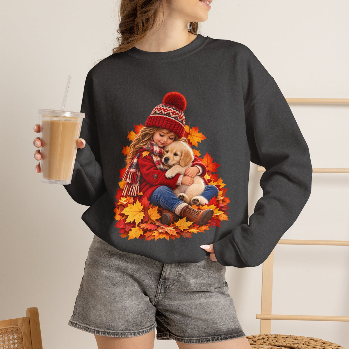 Woman holding a drink dark heather wearing the white Golden Moments girl and puppy fall sweatshirt
