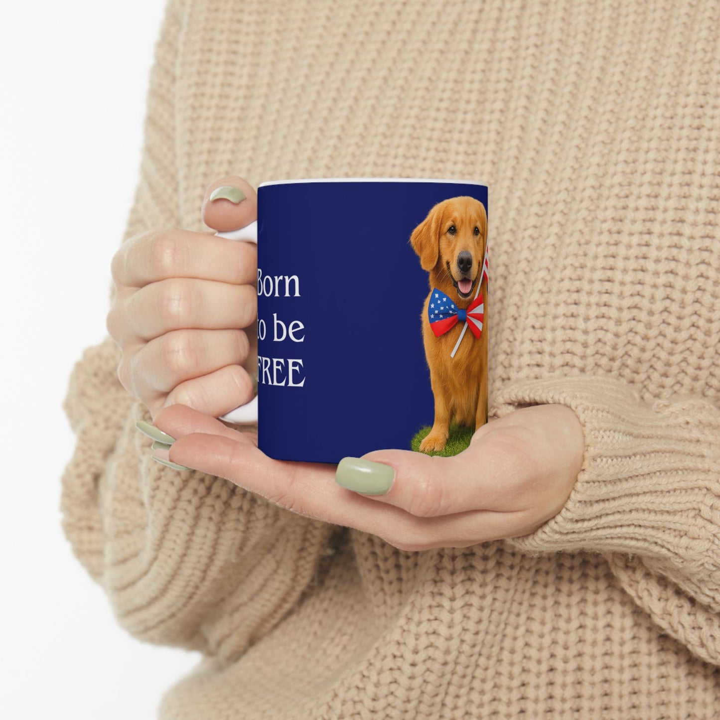 Person holding a mug with a dog design and text, wearing a beige sweater.