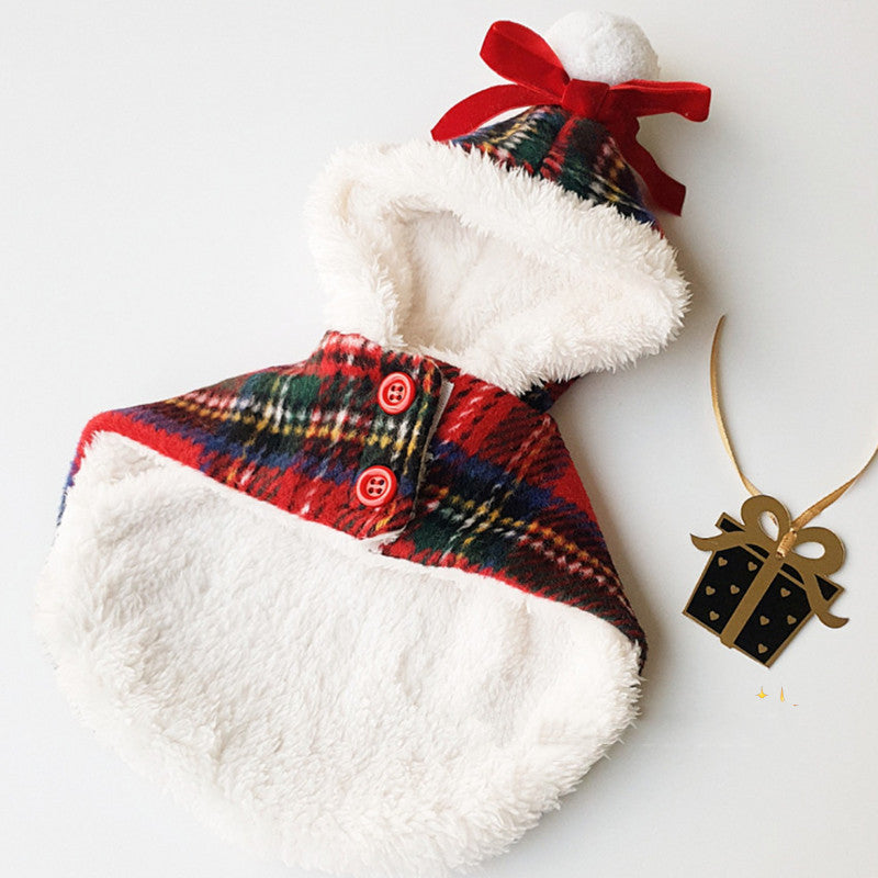 Plaid dog coat with white fur lining and a red bow, next to a gold gift box ornament on a white background.