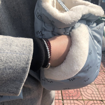 Close-up of a person wearing a textured coat with a fluffy hood, holding a phone.