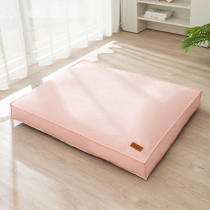 Pink pet bed on a wooden floor with a white curtain in the background